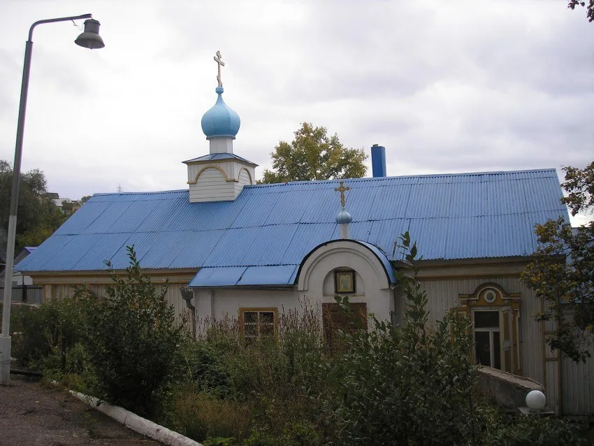 Деревянный храм с голубыми куполами осенью, вид сбоку