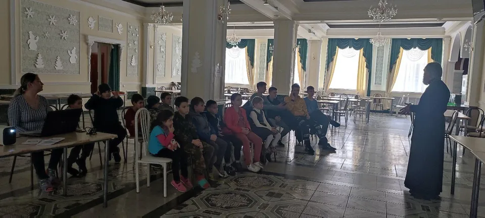 Группа детей сидит в зале на приходском мероприятии